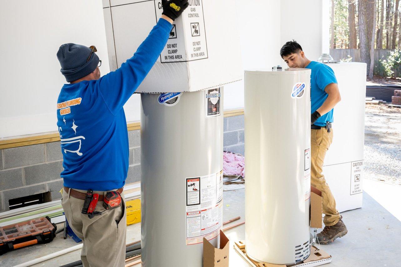 Two plumbers preparing to install water heaters in home.